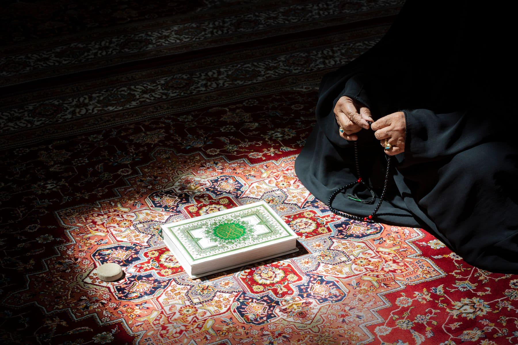 A mushaf and tasbih resting on a prayer mat